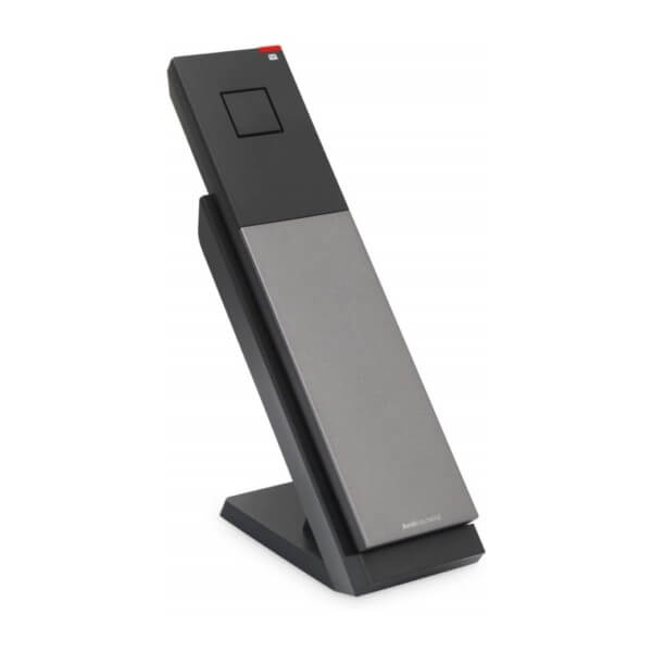 A sleek remote control resting in a charging stand, featuring a modern design with a matte black and silver finish.